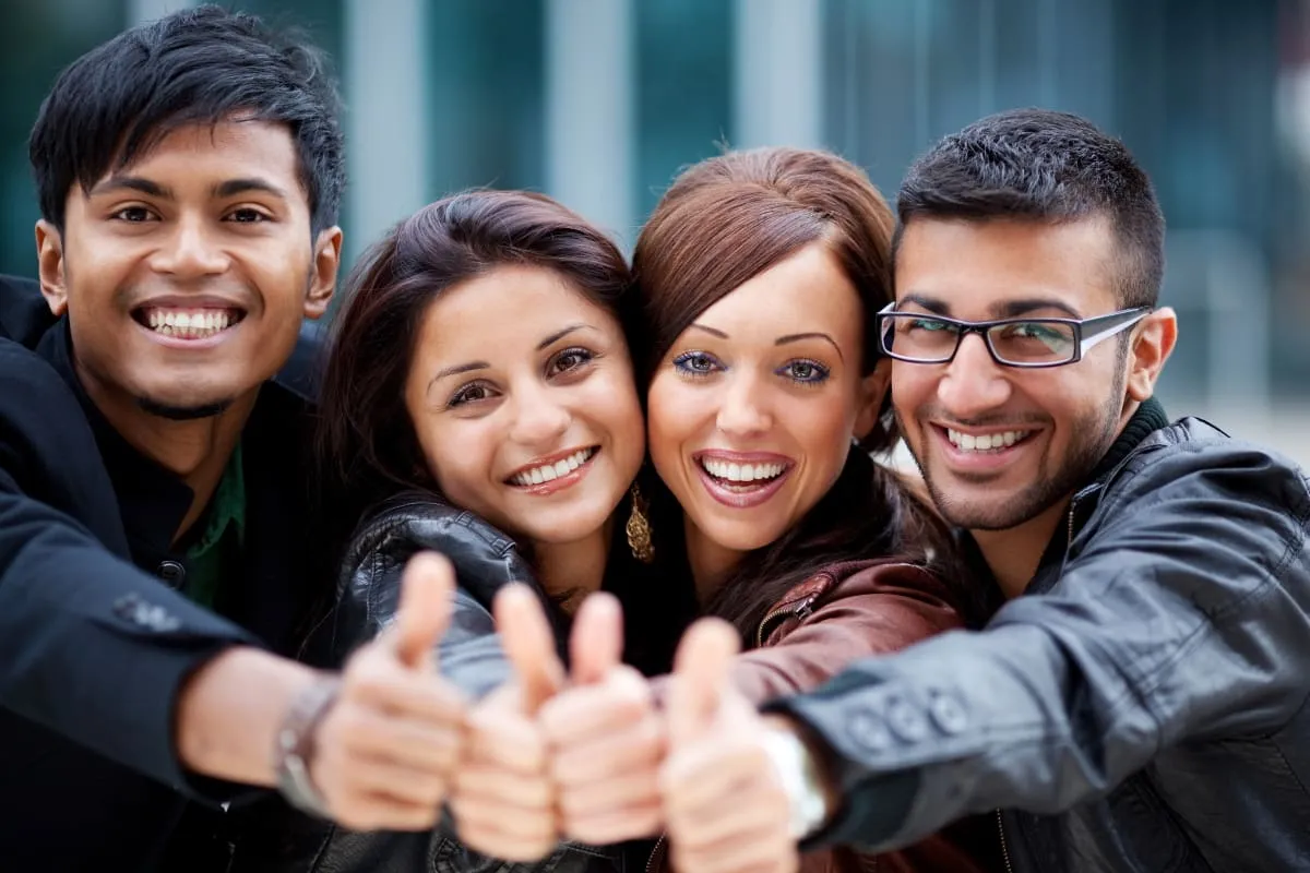 team-collaboration Group of four young people with thumbs up.